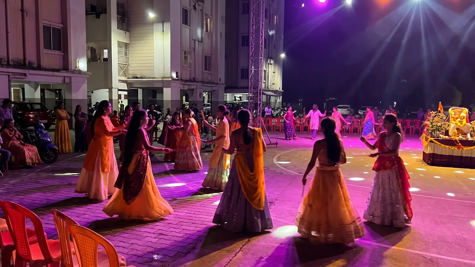 Residents dancing garba under purple stage lights at Gulmohar